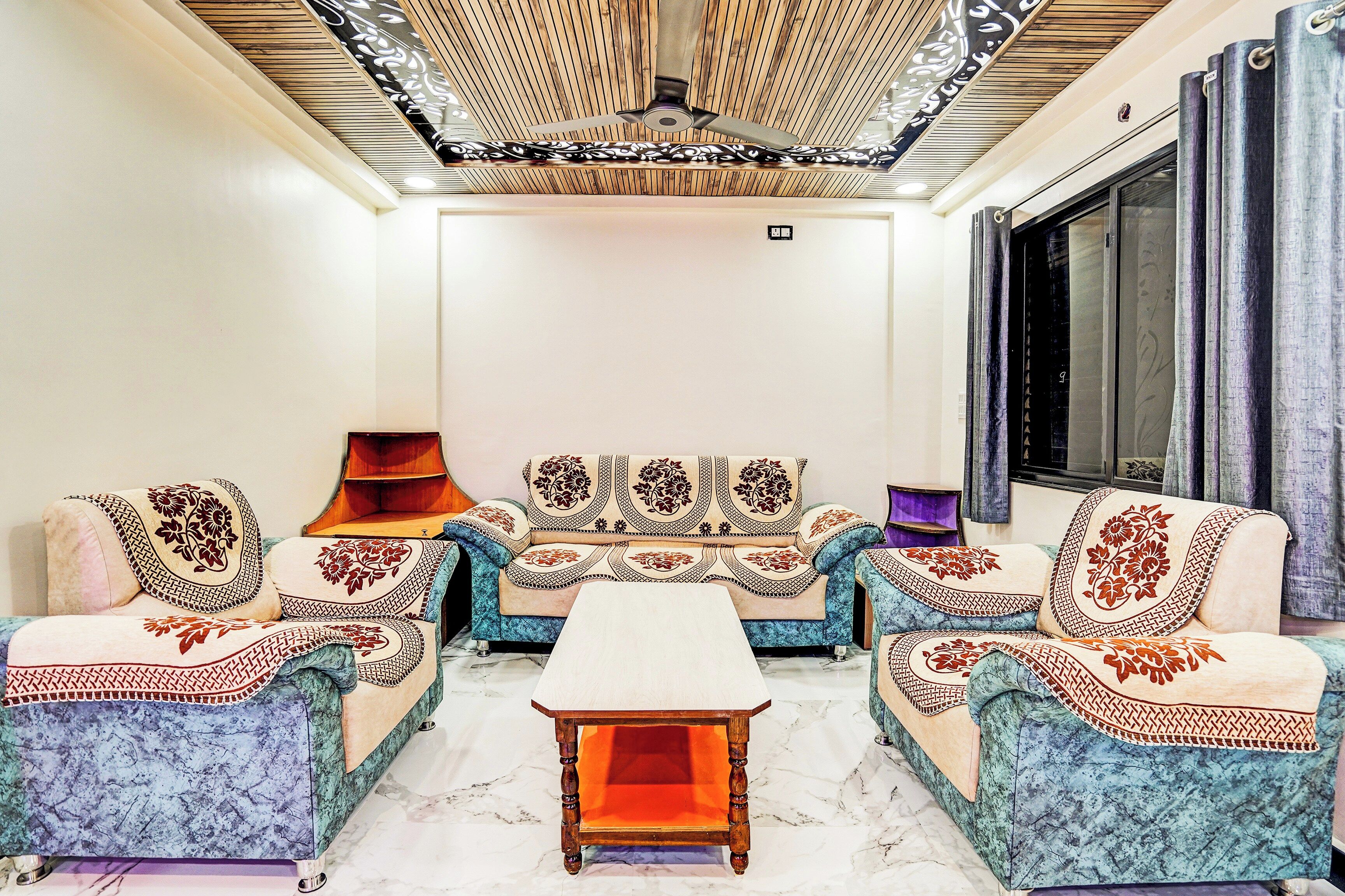 A living room with a sofa set, two armchairs, a coffee table, and a ceiling fan.