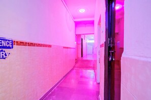 A corridor with tiled walls and a tiled floor, leading to a door with a handle. - Hotel O Sukoon (Nagpur)