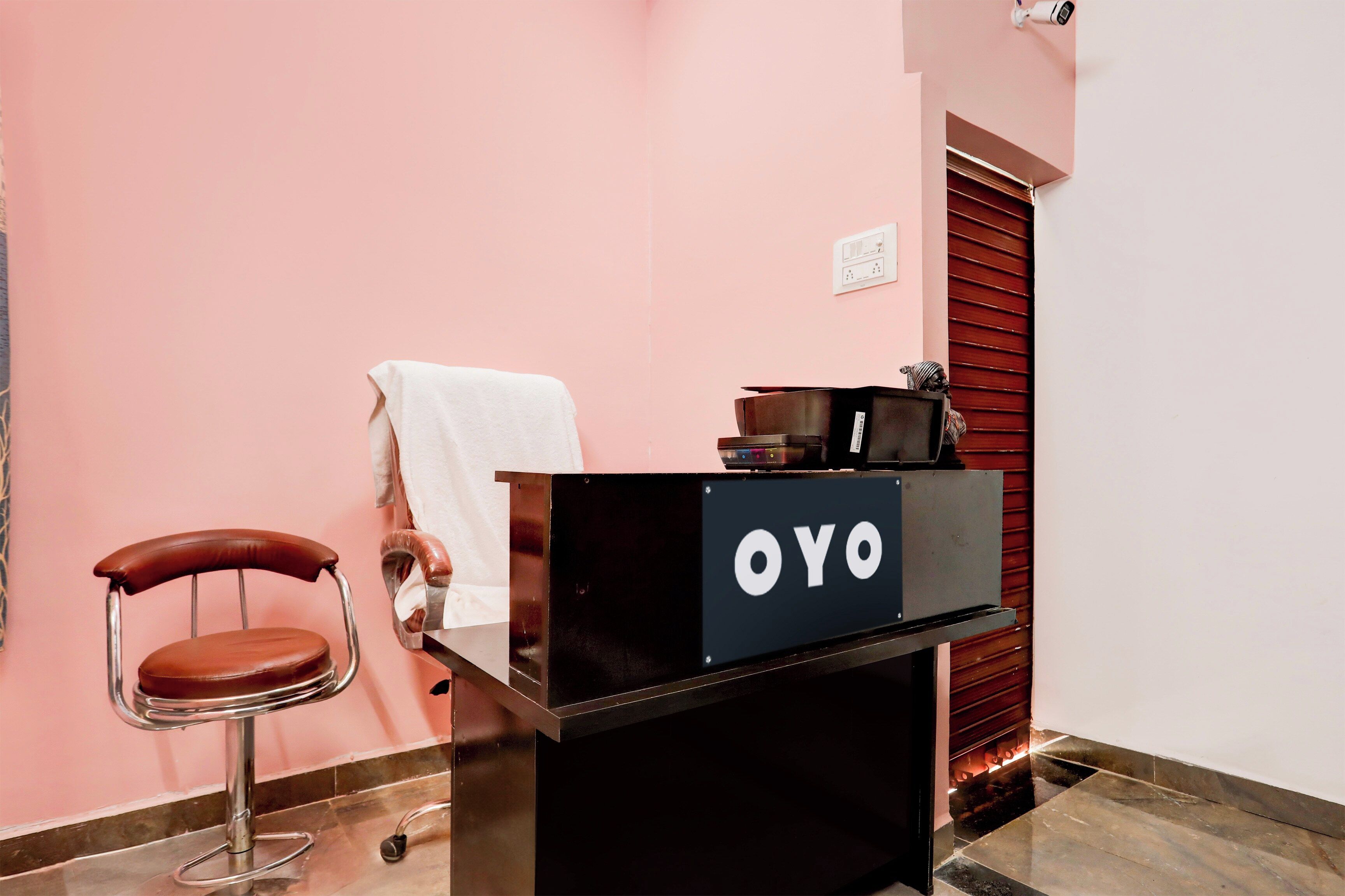 A reception desk with a sign that reads 'OYO' and a chair with a towel on it.