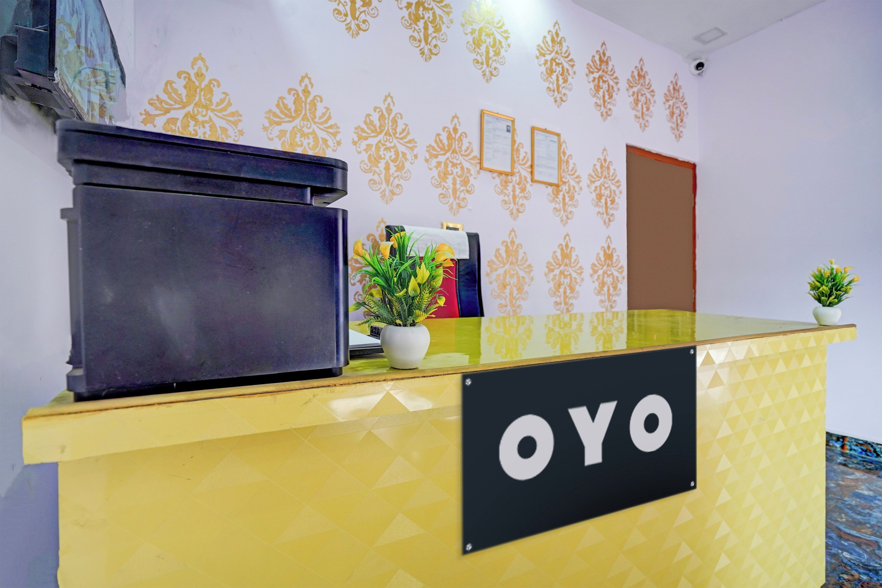 A reception desk with a sign reading 'OYO' and a potted plant on it.
