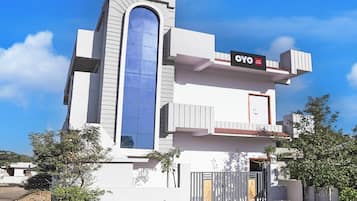 A modern hotel with a prominent vertical glass window, a balcony, and a sign indicating 'OYO HOTEL DELIGHT.'