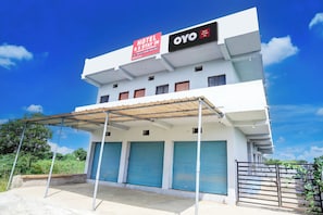 A hotel with a sign indicating 'Hotel Stay In' and 'OYO Inn' branding, featuring a covered entrance and multiple closed garage doors.