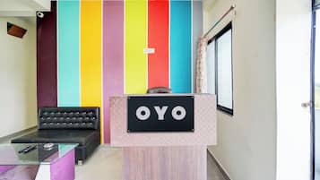 A reception area with a colorful wall, a black leather sofa, a glass table, and a sign that reads 'OYO'.
