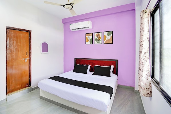 A bedroom with a bed, a ceiling fan, an air conditioning unit, and a window with curtains.