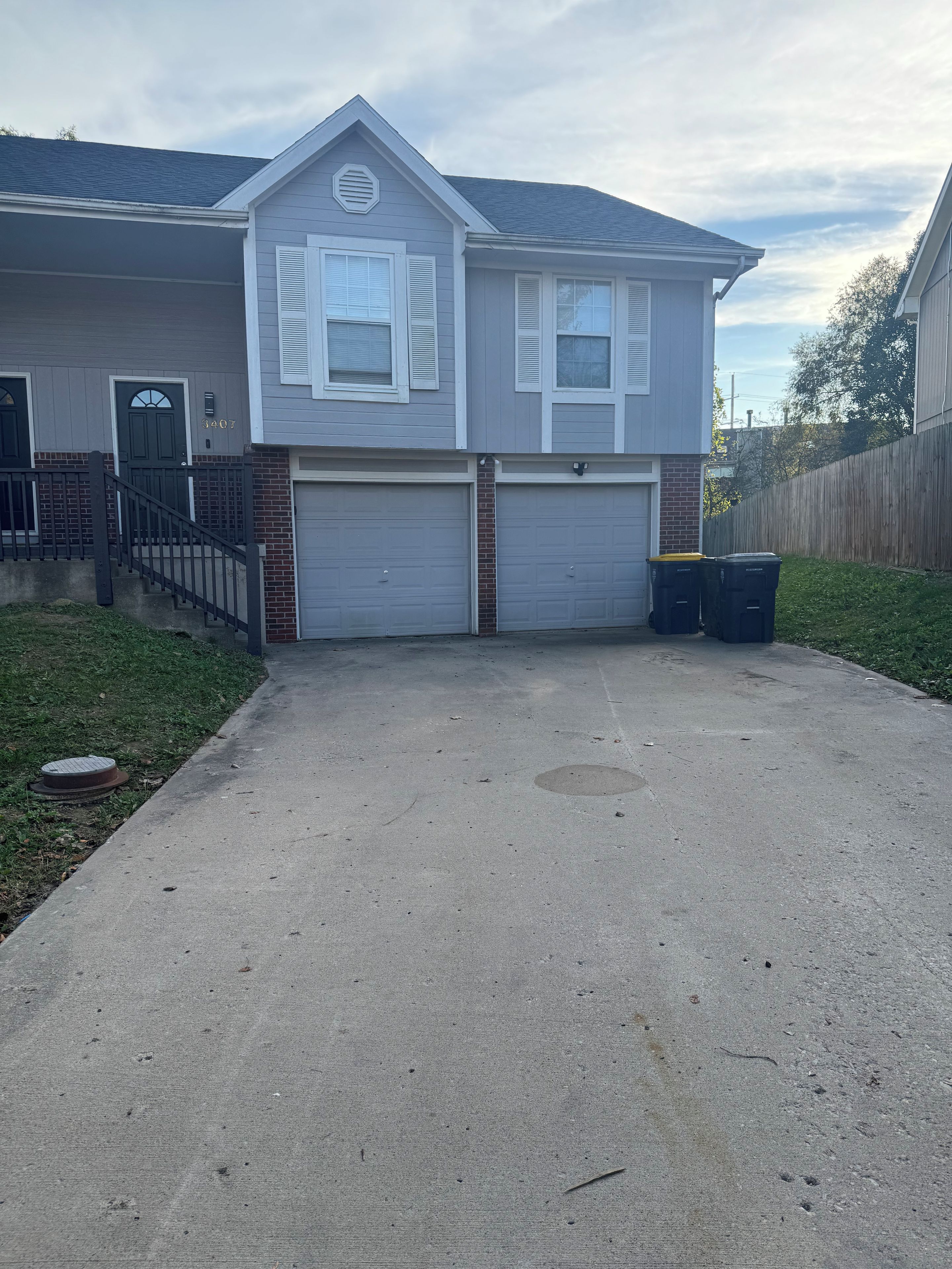 A two-story house with a garage, a front porch, and a brick foundation.