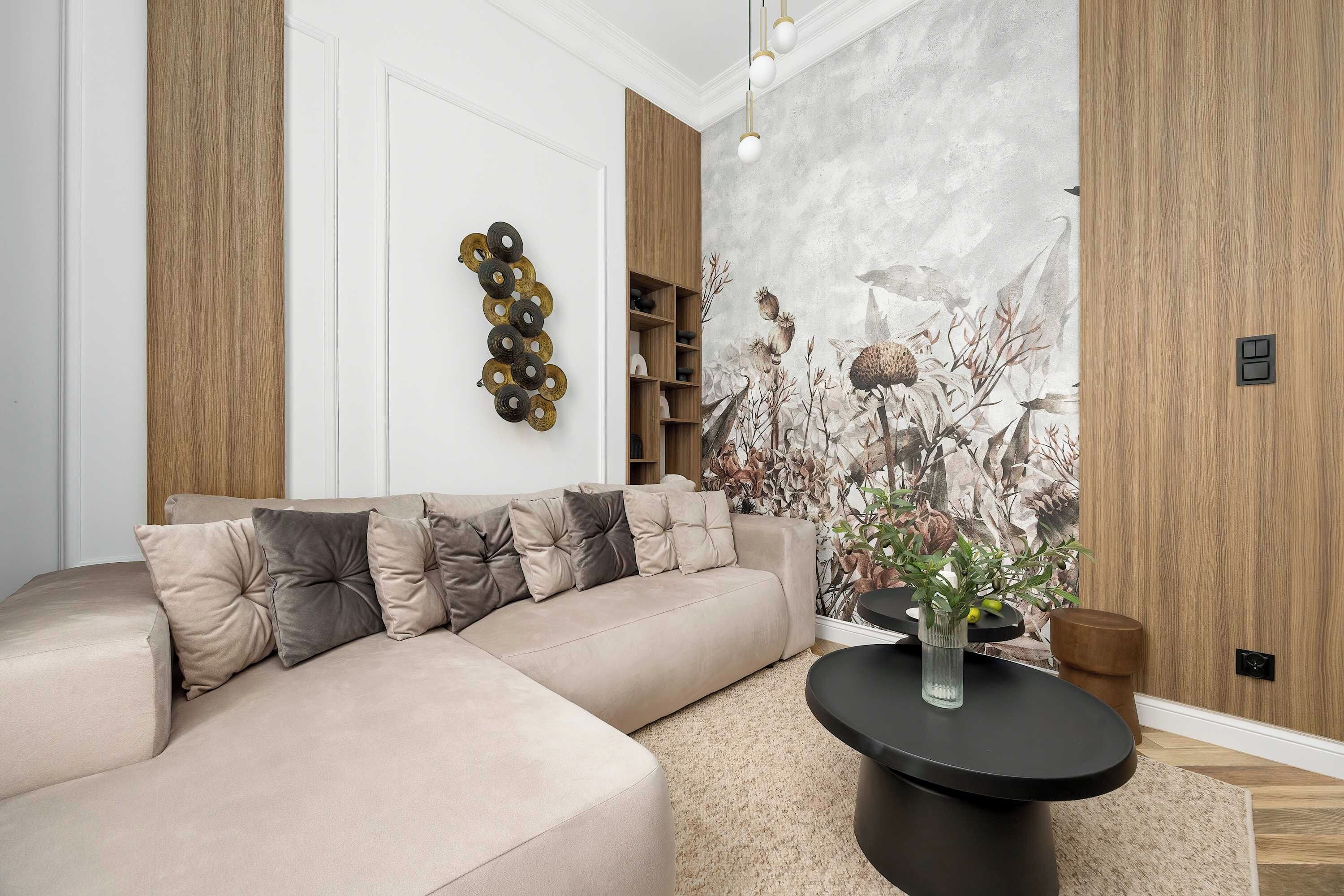 Ein modernes Wohnzimmer mit einem beigen Ecksofa, einem schwarzen Couchtisch und einer Wandmalerei.