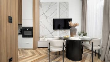 A modern dining area with a round table, four chairs, and a flat-screen TV mounted on the wall.