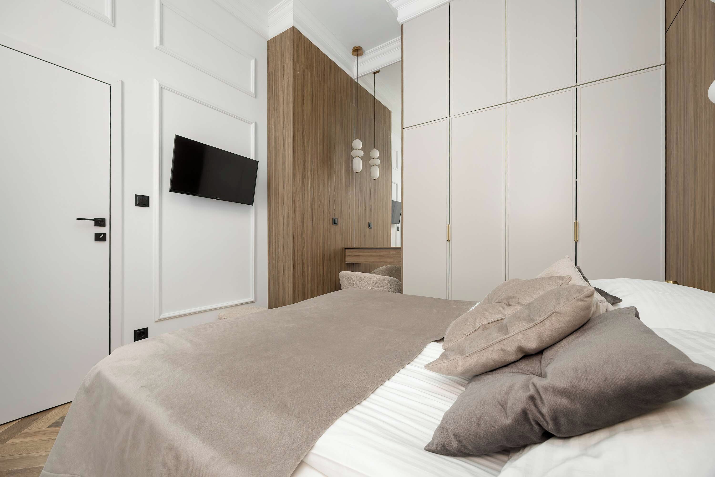 A modern bedroom with a bed, a television, and a wardrobe.