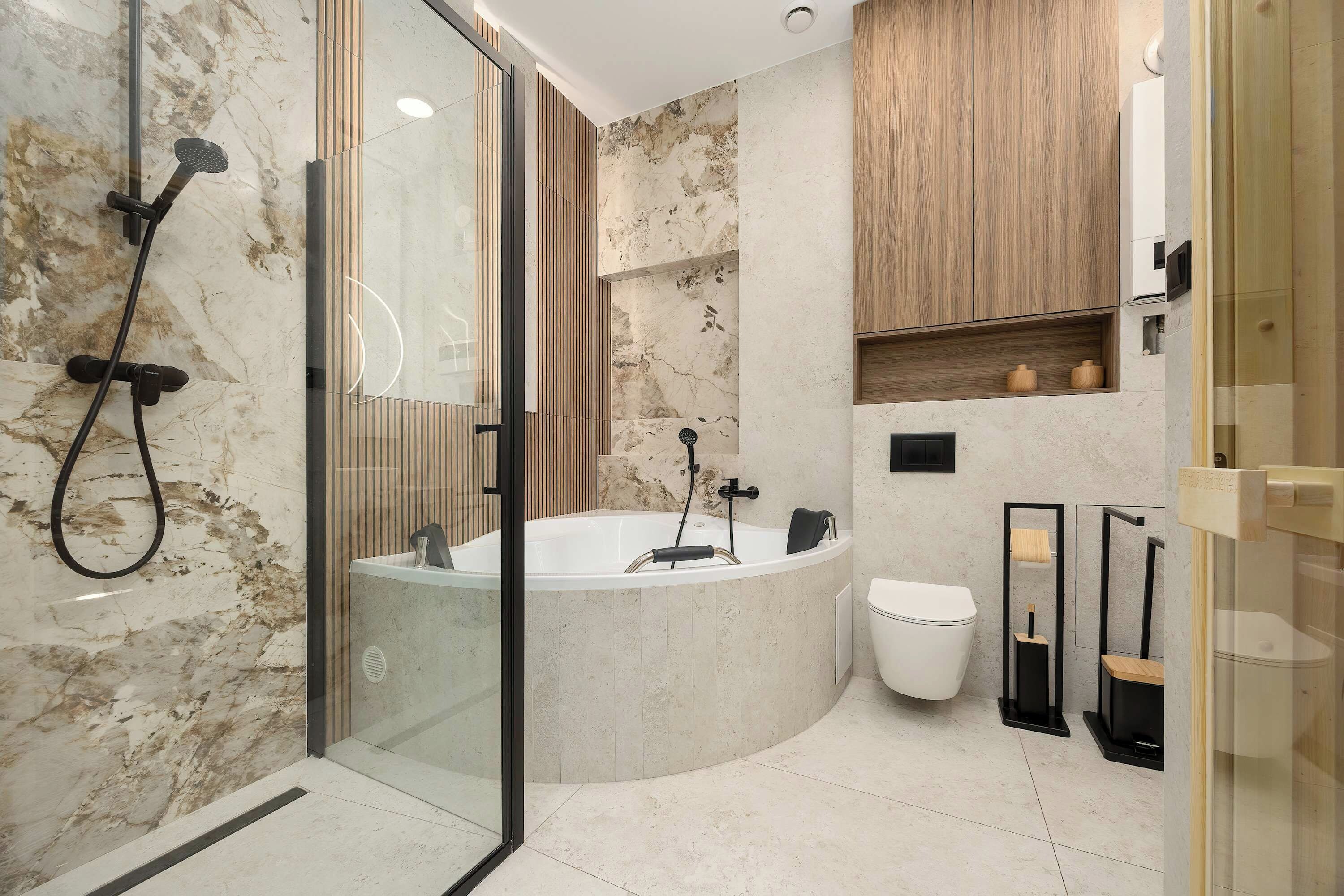 Modern bathroom with a freestanding bathtub, glass shower enclosure and marble-effect tiles.