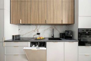 Cozinha moderna com armários de madeira, painel de fundo de mármore, máquina de café e lava-louças.