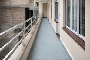 A corridor with a metal railing, a tiled floor, and windows on one side. - Hotel Sherpa Soul (Kathmandu)