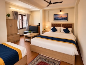 A hotel room with two beds, a sofa, a desk, a wardrobe, a ceiling fan, and a painting on the wall. - Hotel Sherpa Soul (Kathmandu)