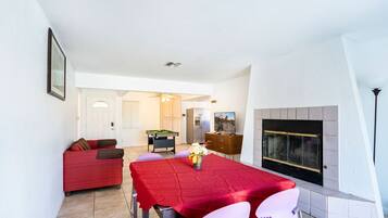 A dining area with a red table, chairs, and a fireplace.