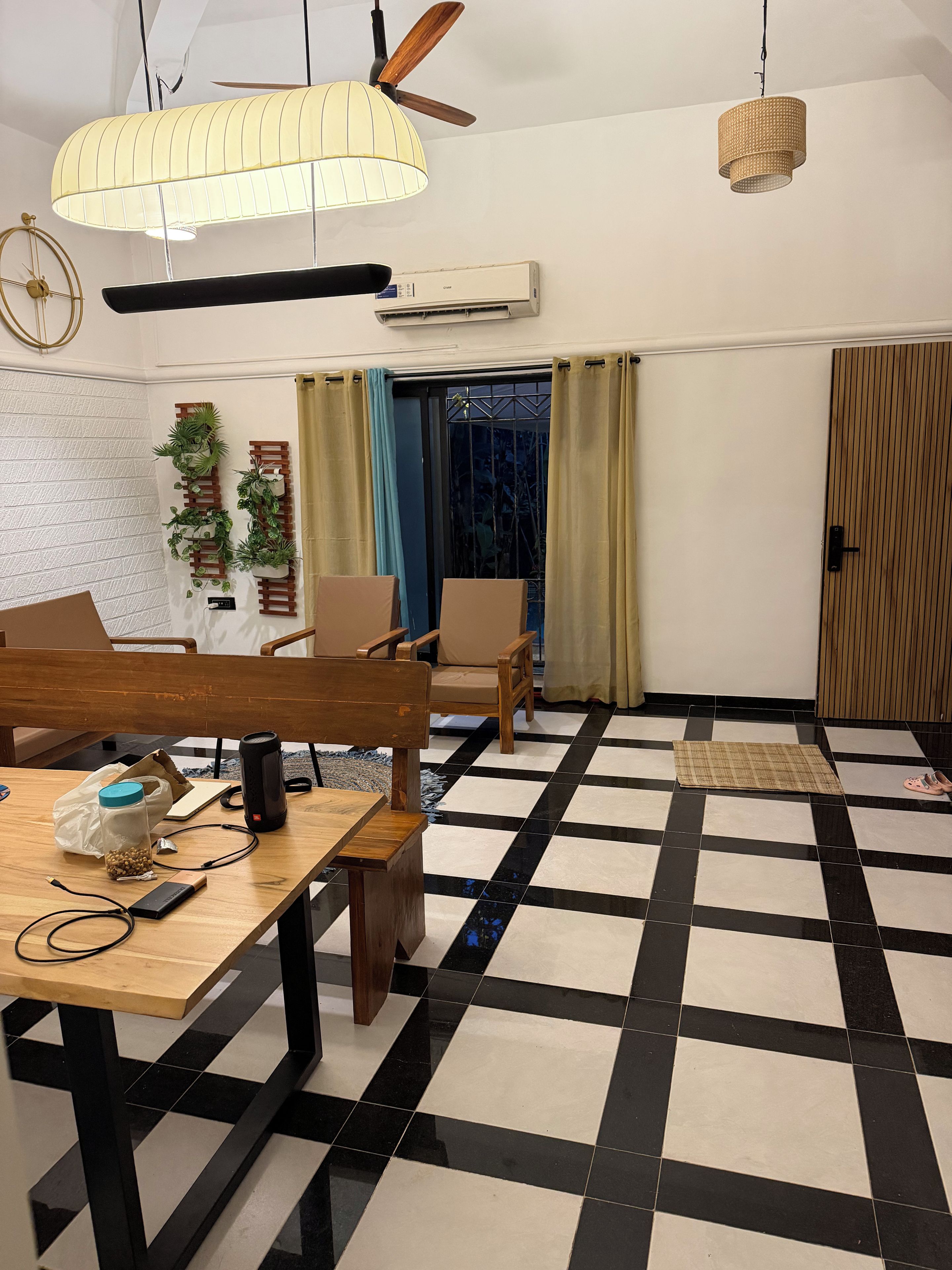 A room with a checkered floor, a dining table with chairs, a ceiling fan, and a wall-mounted air conditioner.