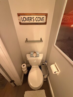 A bathroom with a toilet, a towel rack, and a sign that reads 'LOVER'S COVE'. - Harbor breeze house-1bd 1.5 bath w private access to kitchen en-suite and den. (Los Angeles)