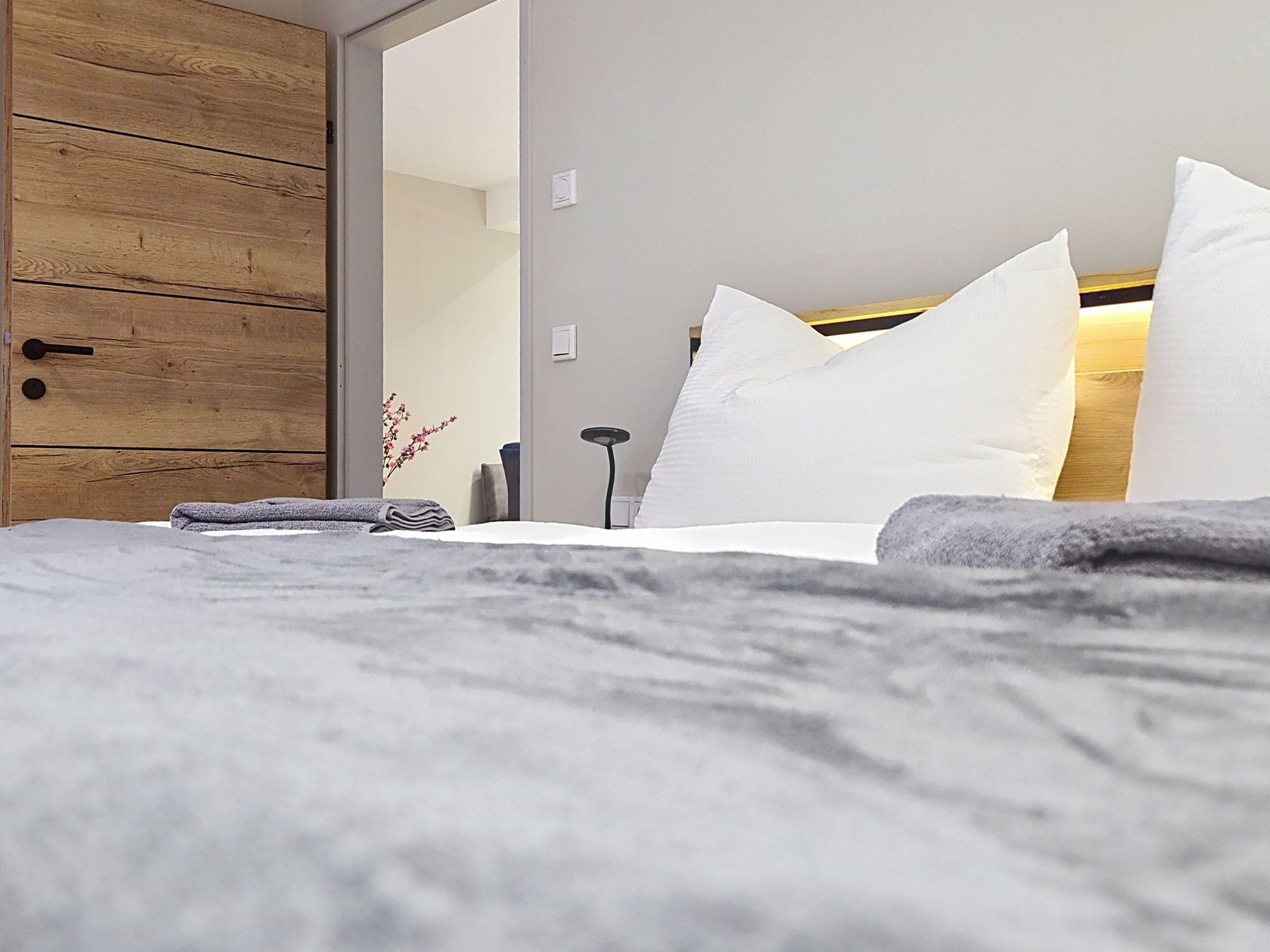 A hotel room with a bed, a wooden wardrobe, a bedside table, and a nightstand.