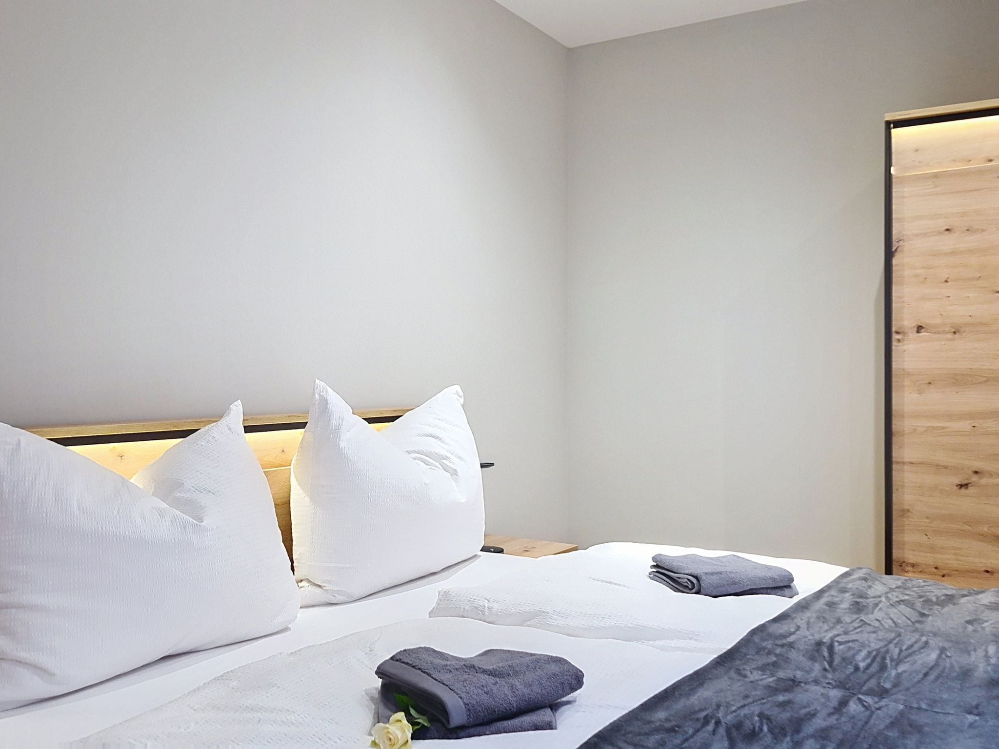 Ein Hotelzimmer mit einem Bett, Kissen, einem gefalteten Handtuch und einer Holzwand.