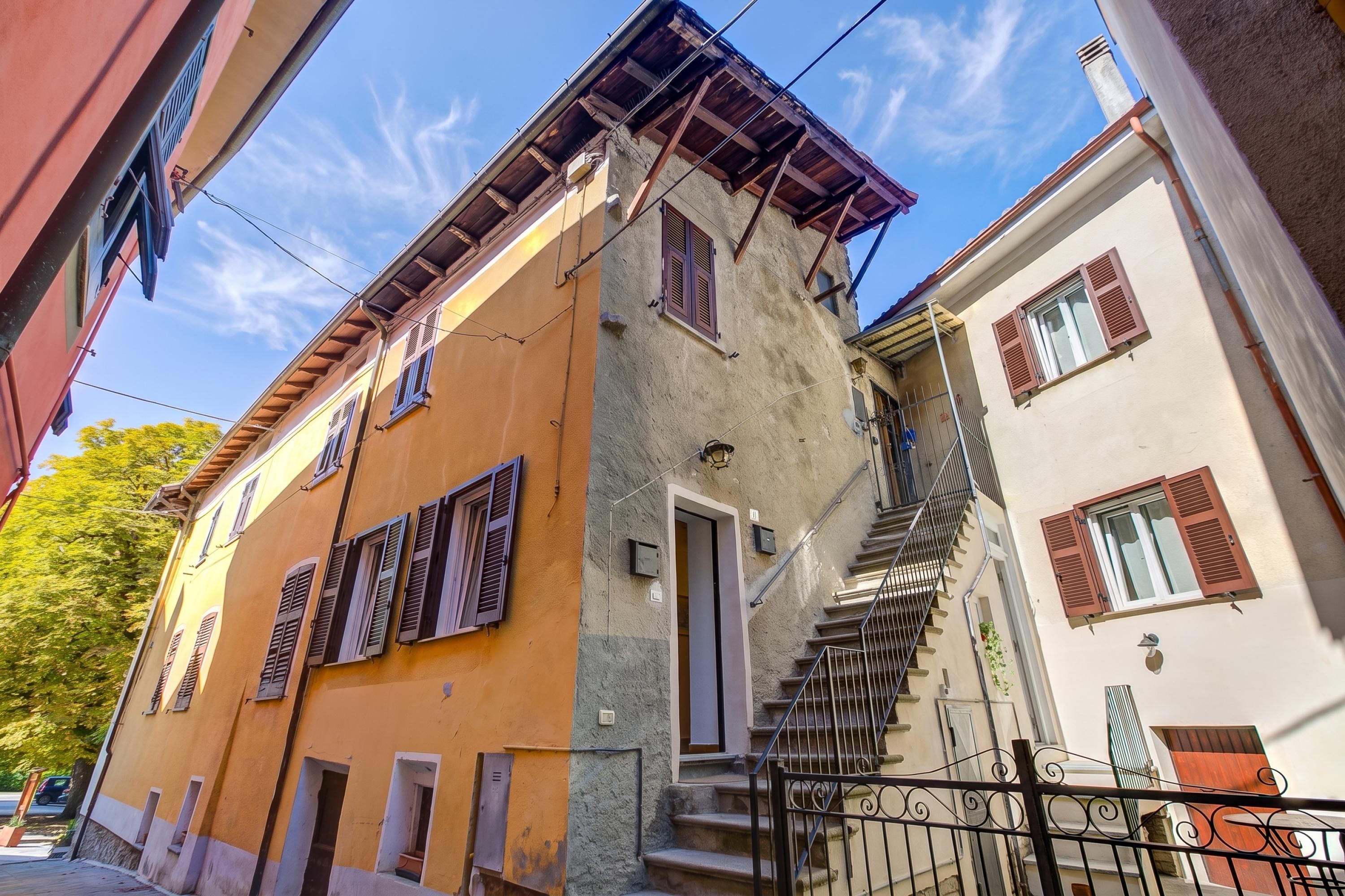A narrow street with buildings featuring balconies and a visible staircase.