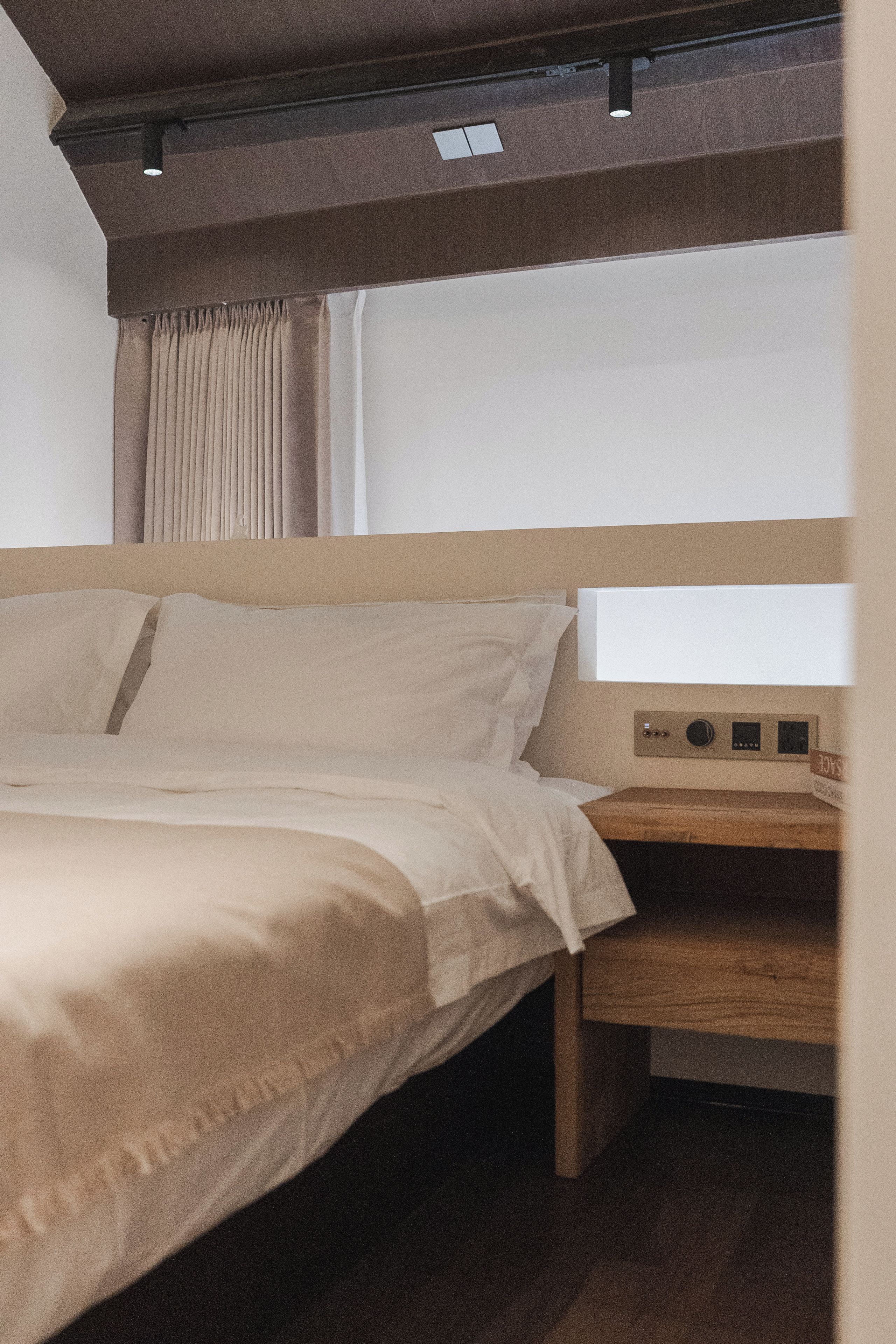 Une chambre d’hôtel avec un lit, une table de chevet et une fenêtre avec des rideaux.
