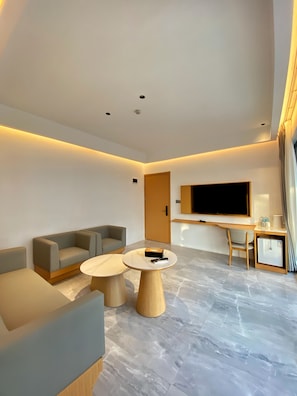 A modern living room with a sofa, two coffee tables, a flat-screen TV, and a small refrigerator. - diver's home resort (Panglao)