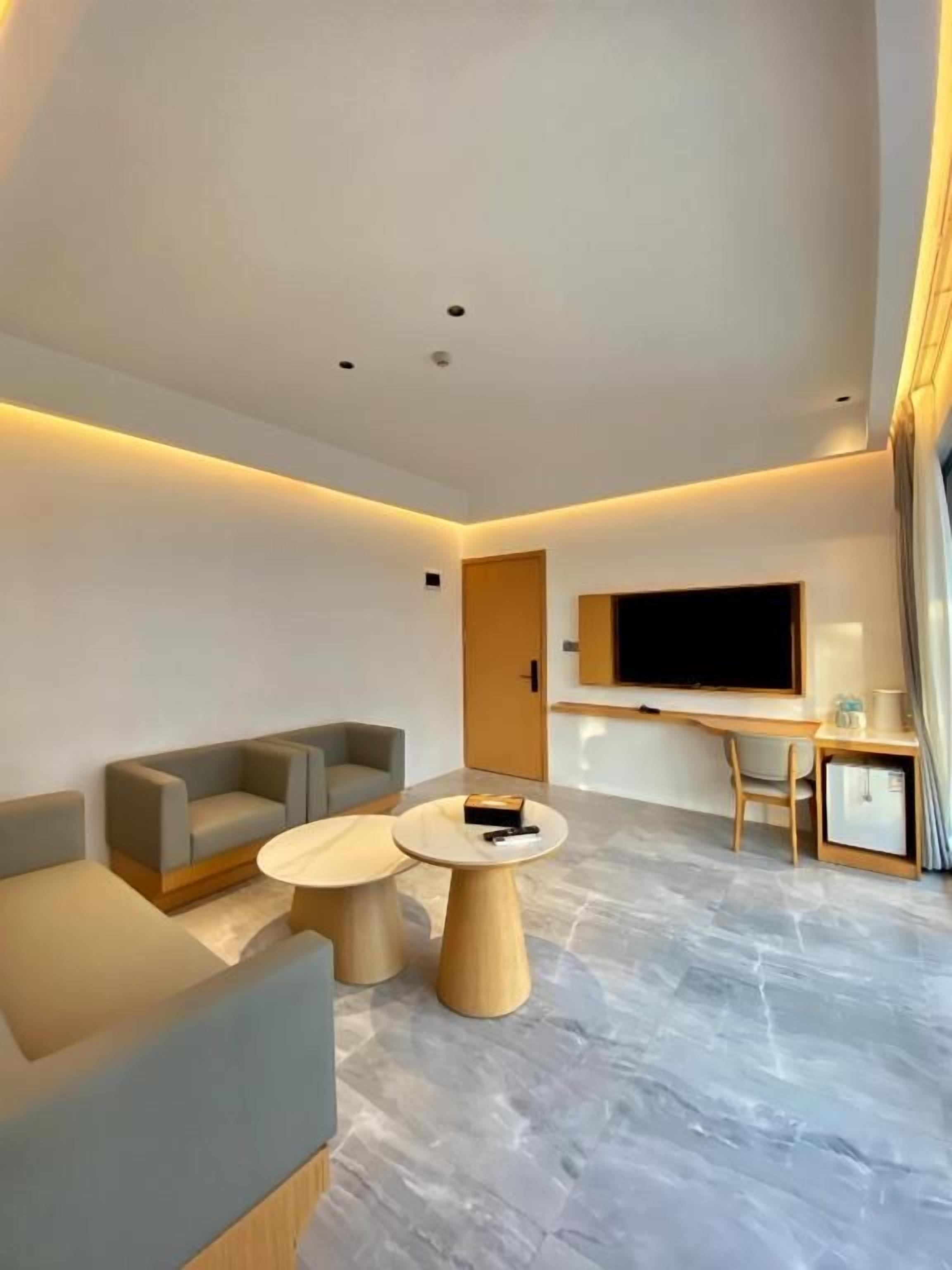 Una sala de estar moderna con un televisor de pantalla plana, dos sofás, una mesa de centro y un escritorio pequeño con una silla.