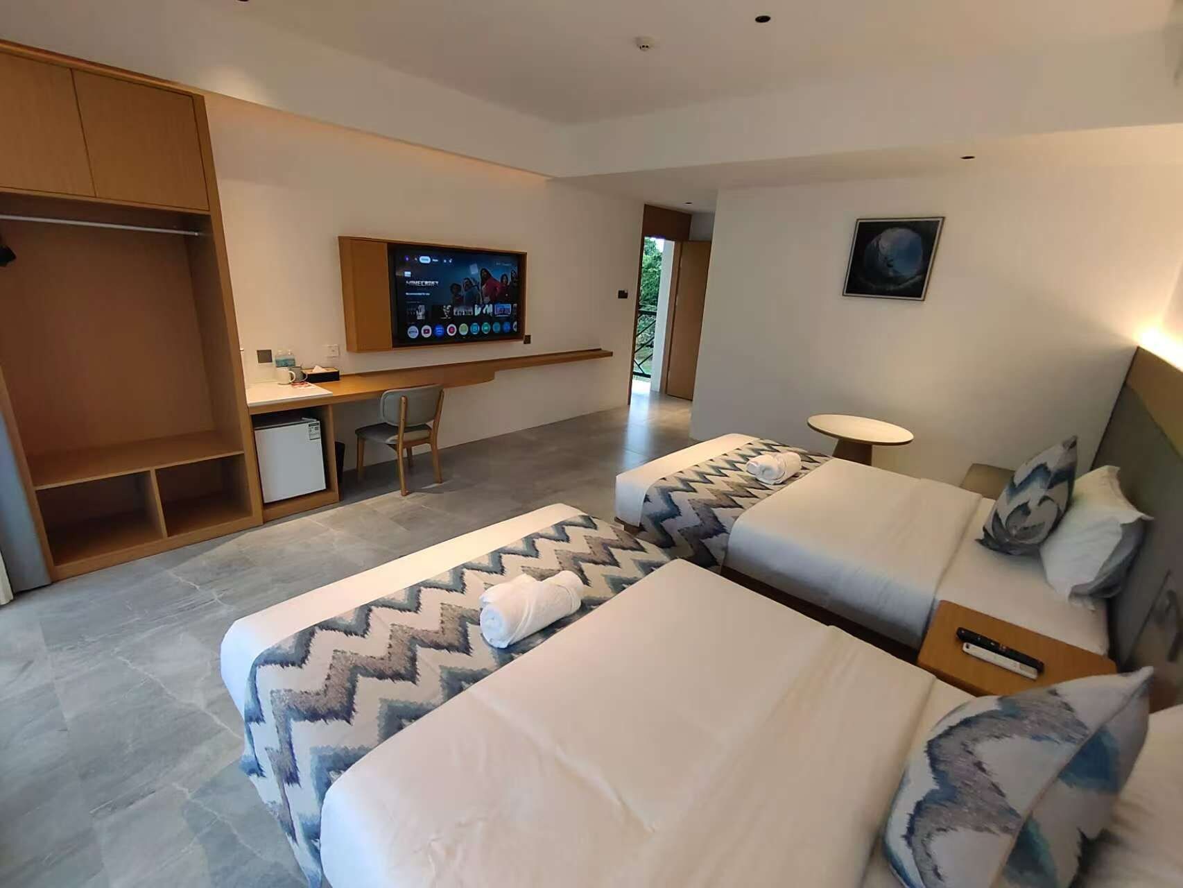 Una habitación de hotel con dos camas, un escritorio, un televisor y una mesita.