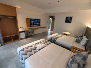 Una habitación de hotel con dos camas, un escritorio, un televisor y una mesita.