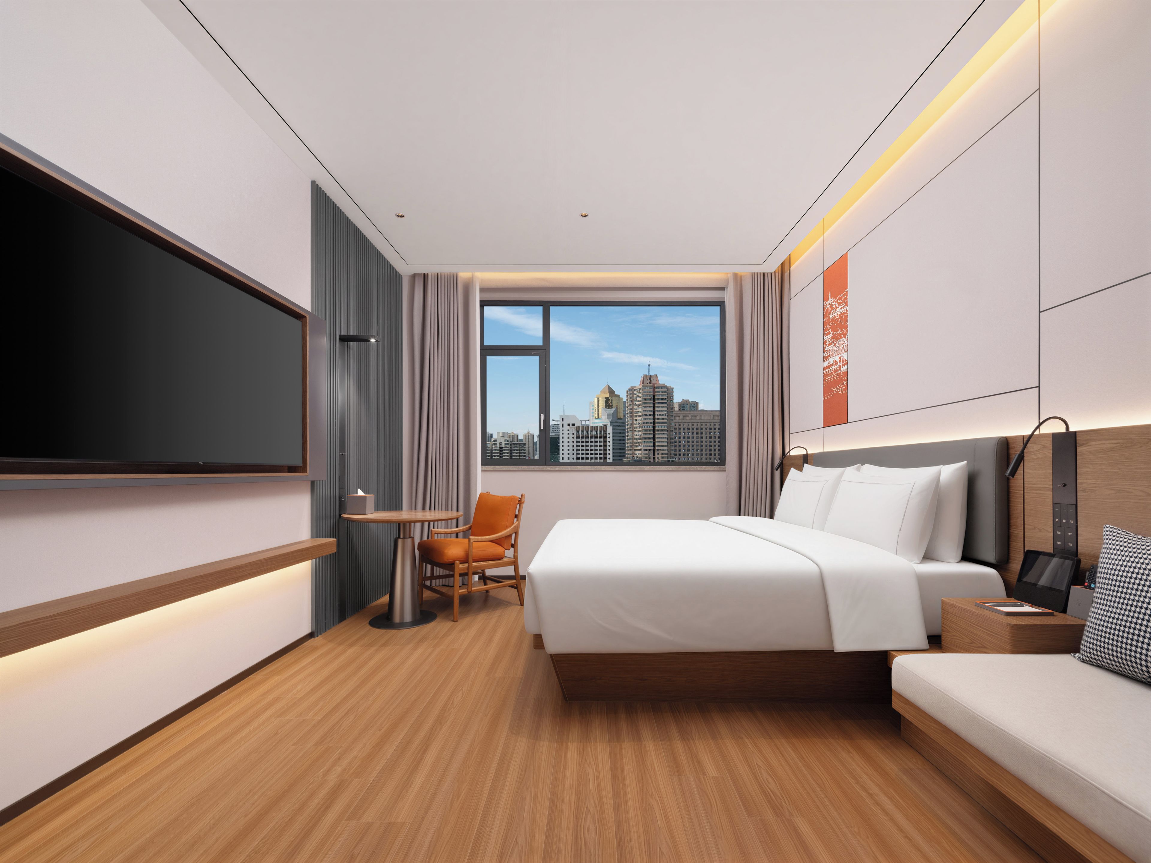 A hotel room with a bed, a sofa, a TV, a window with a city view, and a small table with a chair.