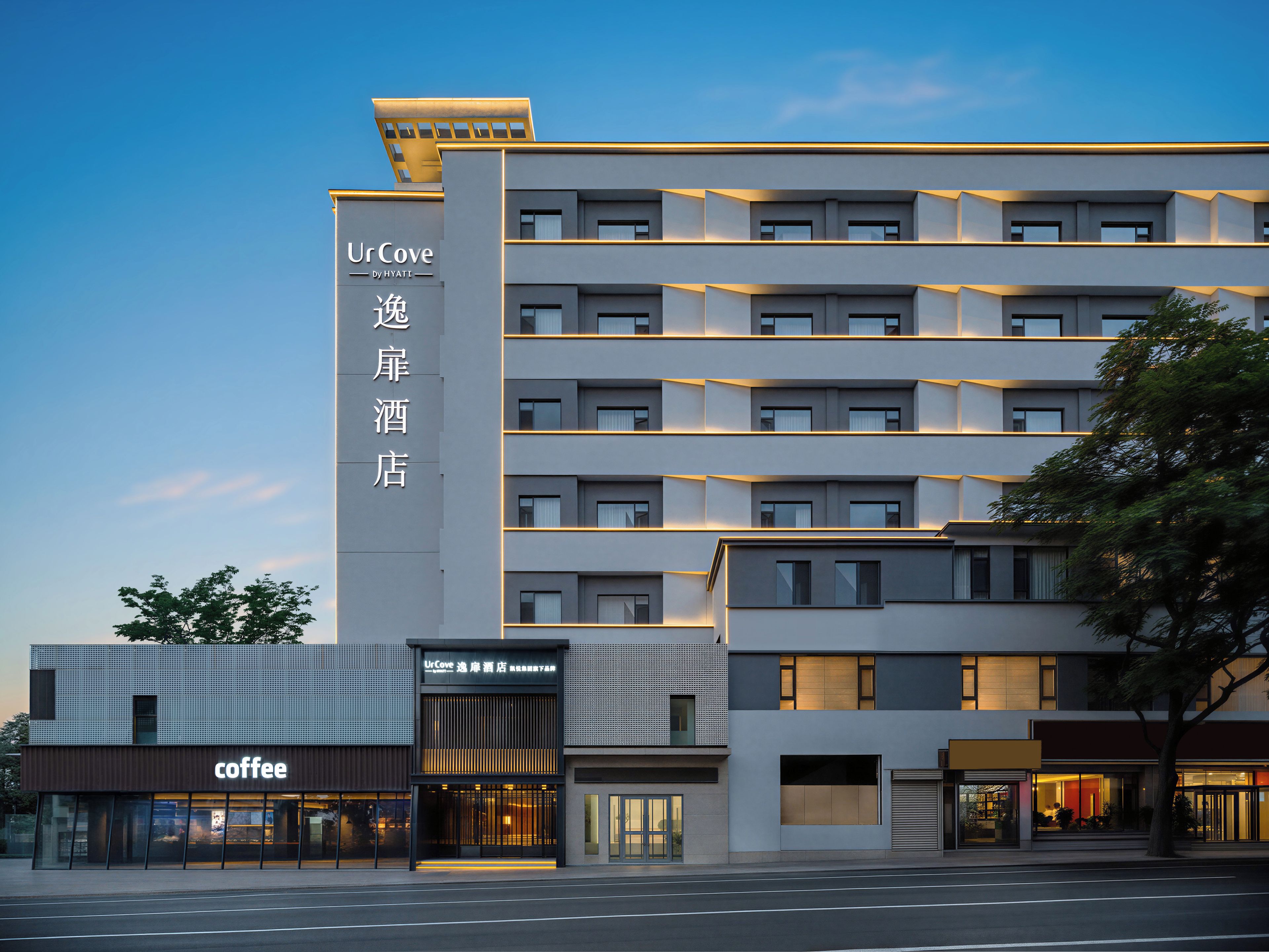 A multi-story hotel with a modern facade, a coffee shop on the ground floor, and signage in both English and another language.