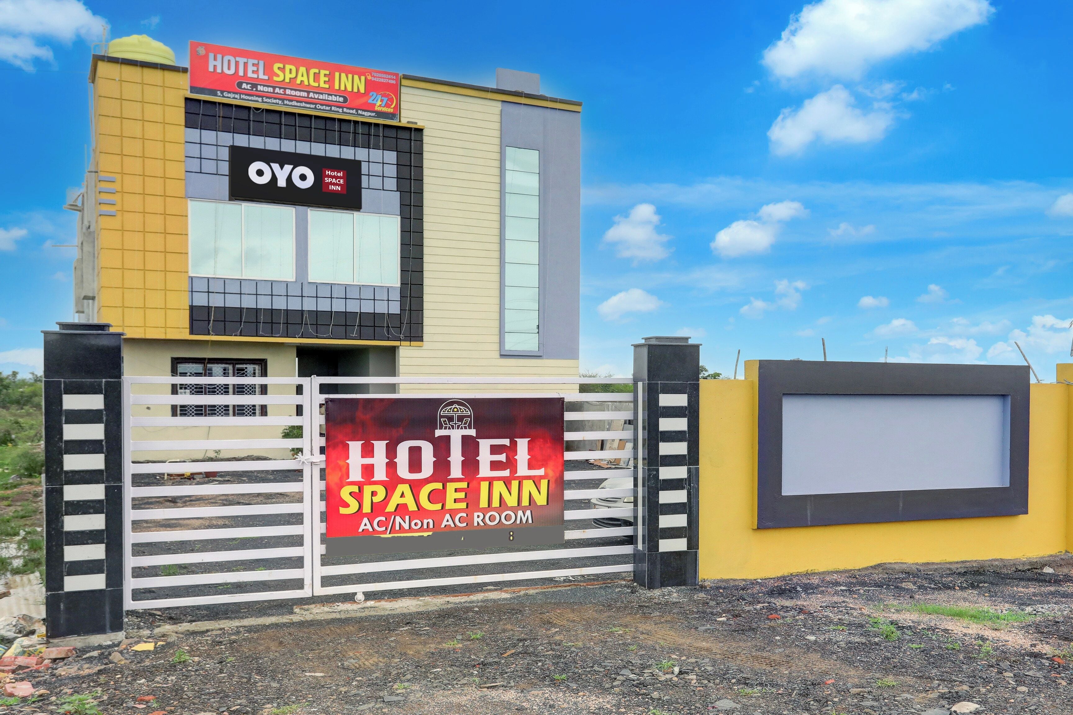 A hotel space inn with a prominent signboard, a gated entrance, and a clear sky.