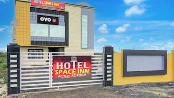 Un hotel con espacio interior, un cartel llamativo, una entrada con portón y cielo despejado.