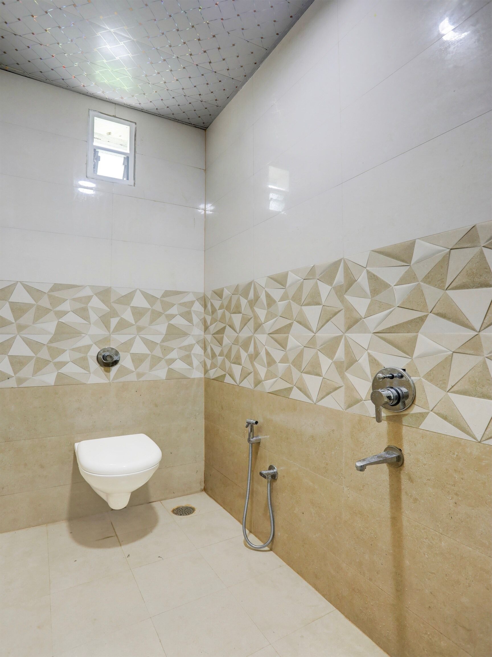 Une salle de bain équipée de toilettes, d’une douche et d’un mur orné d’un motif géométrique.