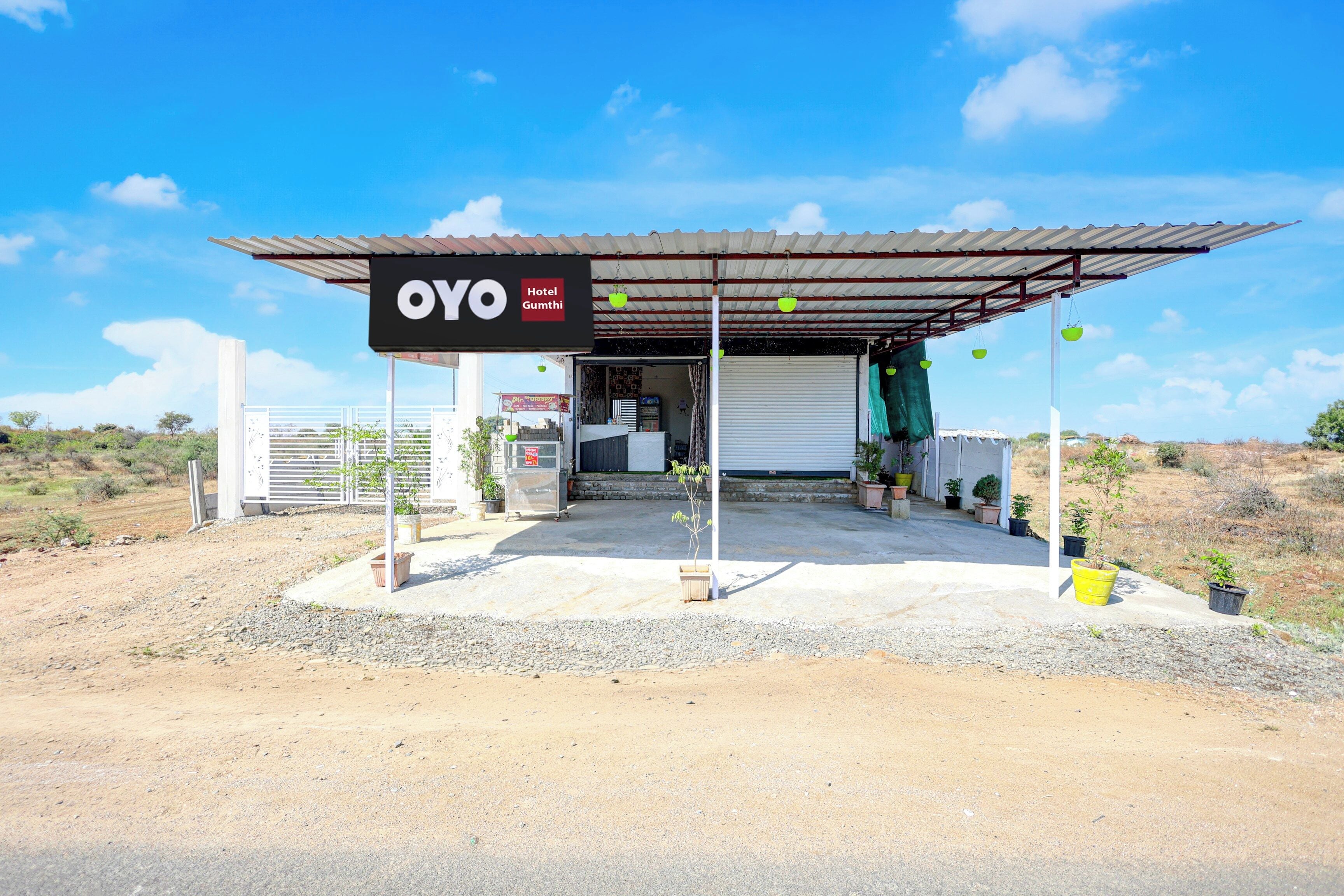 A hotel named OYO Gumthi with a covered entrance and potted plants.