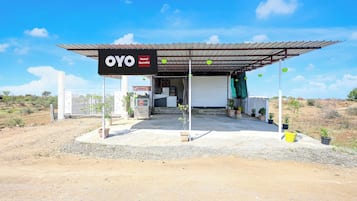 Hotel OYO Gumthi, com entrada coberta e plantas em vasos.