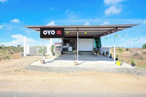 Un hotel anomenat OYO Gumthi amb entrada coberta i plantes en testos.