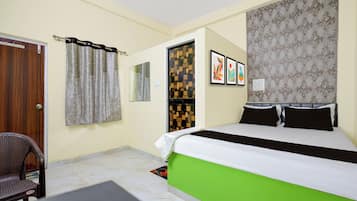 Une chambre d’hôtel avec un lit, une chaise, une armoire et un miroir.