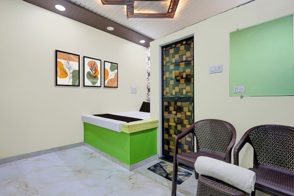 A reception area with a green desk, three framed artworks, a patterned door, and two wicker chairs. - HOTEL O GUMTHI (Kamptee)