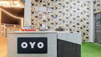 A reception desk with a sign reading 'OYO' and a wall decorated with vintage-style postcards.