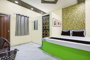 Ein Hotelzimmer mit Bett, Sessel, Badezimmer mit Spiegel und Wand mit gerahmten Bildern.
