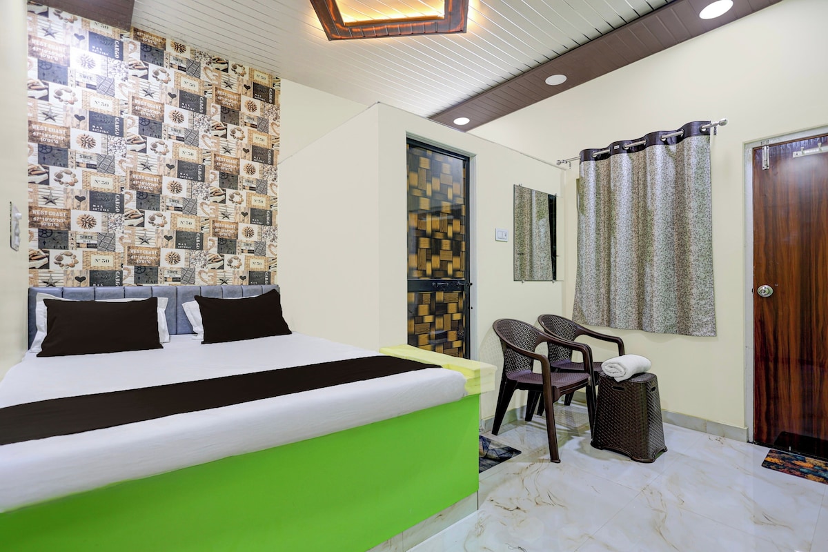Ein Hotelzimmer mit einem Bett, einer Sitzecke mit Stühlen, einer Holztür und einer Wand mit Muster.