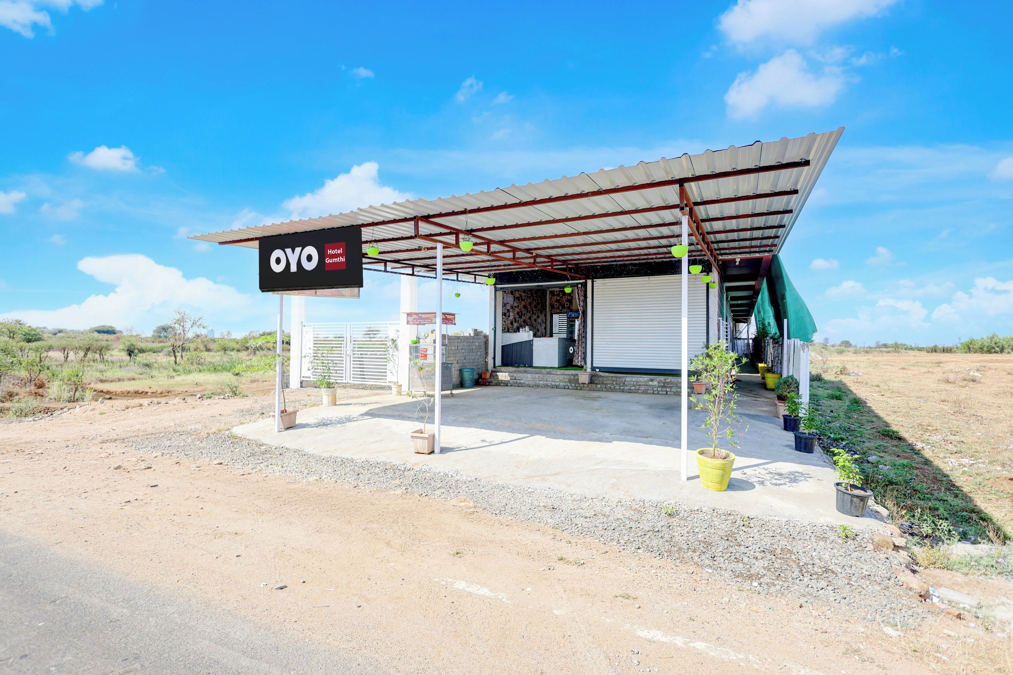 A small, single-story building with a corrugated metal roof, a signboard, and a few potted plants.