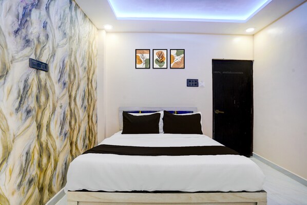 A hotel room with a bed, a wall with abstract art, and a door. - HOTEL O HAVELI INN (Hingna)