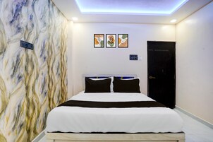 Habitación de hotel con una cama, una pared con arte abstracto y una puerta.