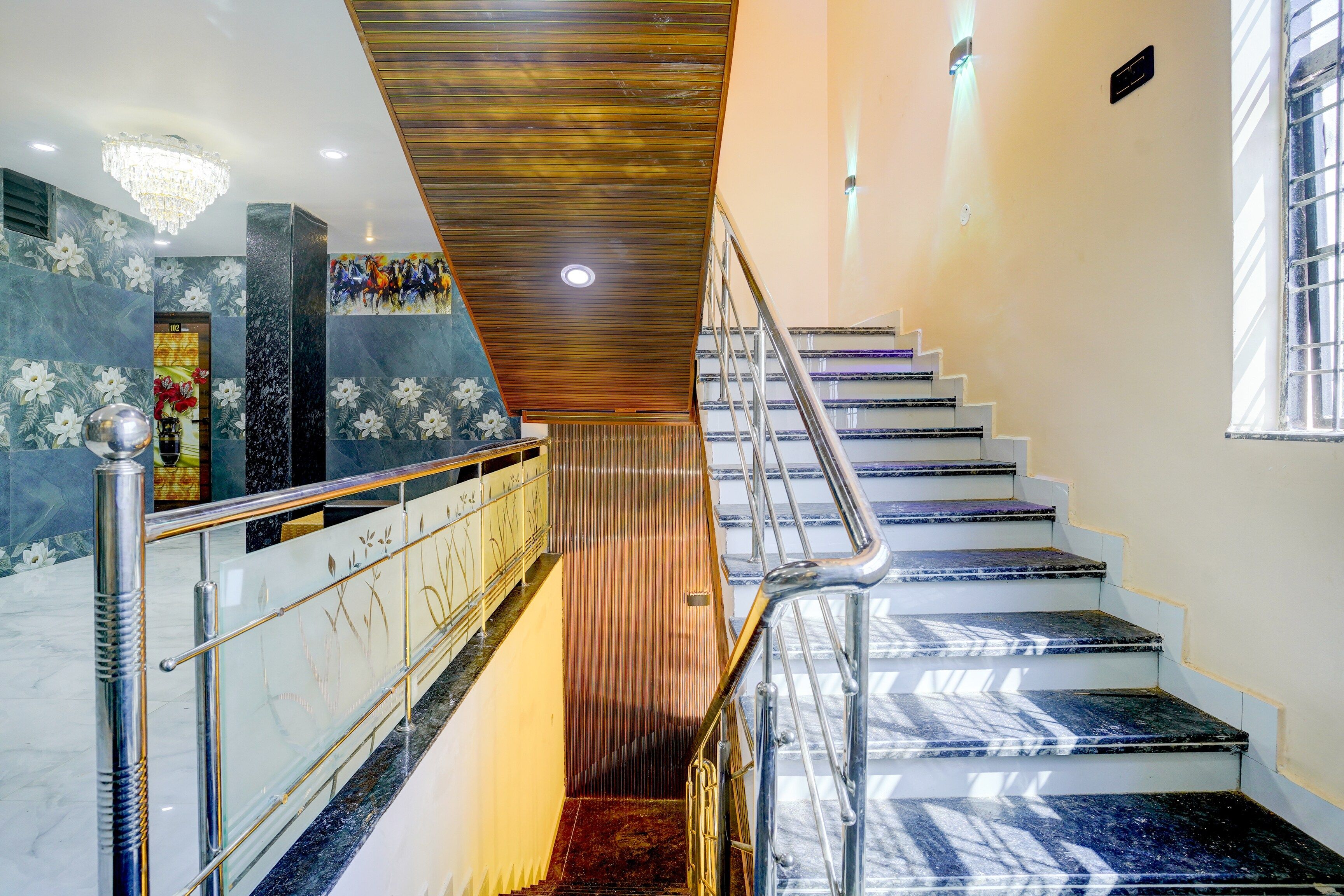 Una escalera con barandilla de madera y escalones de mármol.