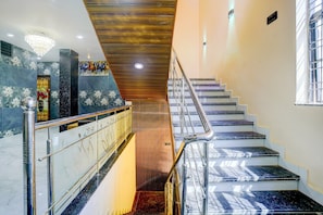 Uma escadaria com corrimão de madeira e degraus de mármore.