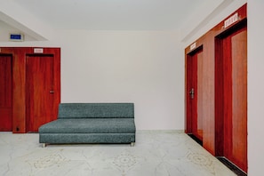 A room with a sofa, two wooden doors, and a tiled floor.