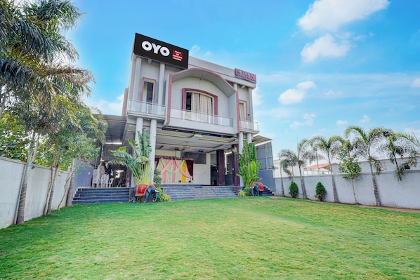 A hotel with a prominent sign, a covered entrance, and a well-maintained lawn.