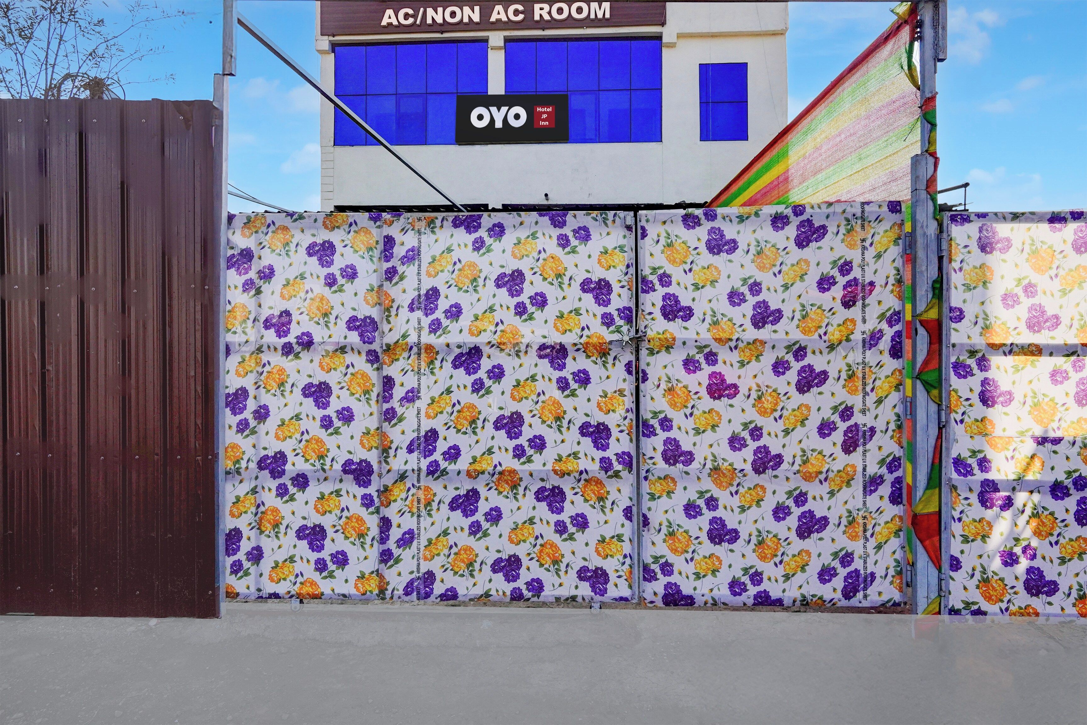 A hotel entrance with a floral-patterned gate, a sign for 'AC/NON AC ROOM', and a visible 'OYO Hotel' sign.