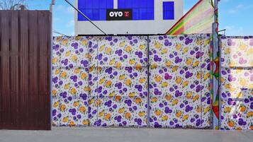 A hotel entrance with a floral-patterned gate, a sign for 'AC/NON AC ROOM', and a visible 'OYO Hotel' sign.