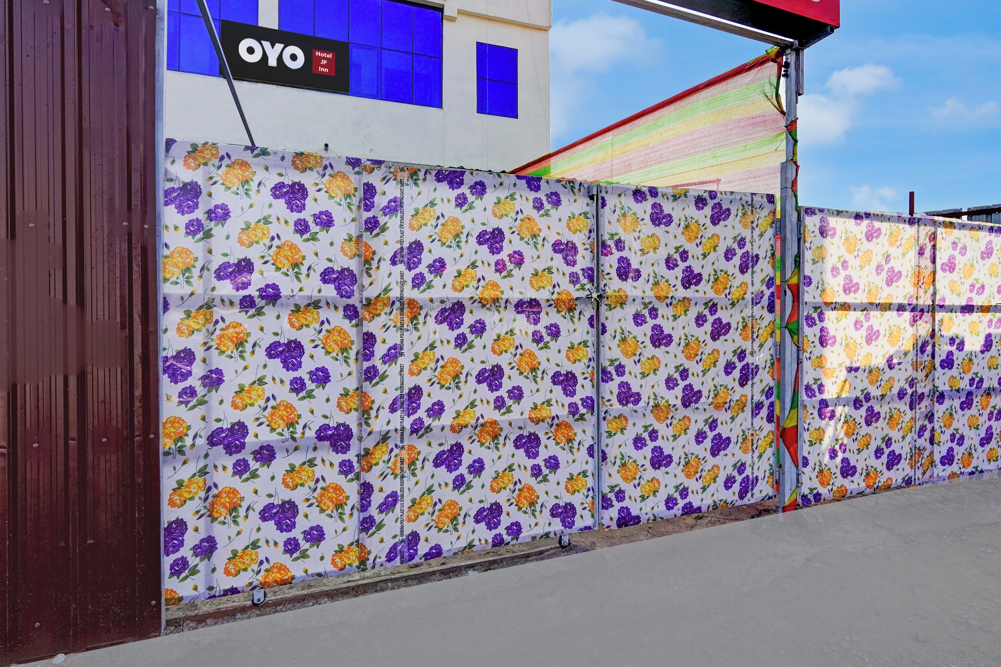 A building with a floral-patterned fence, a sign for 'OYO Hotel Japan Inn,' and a clear sky.